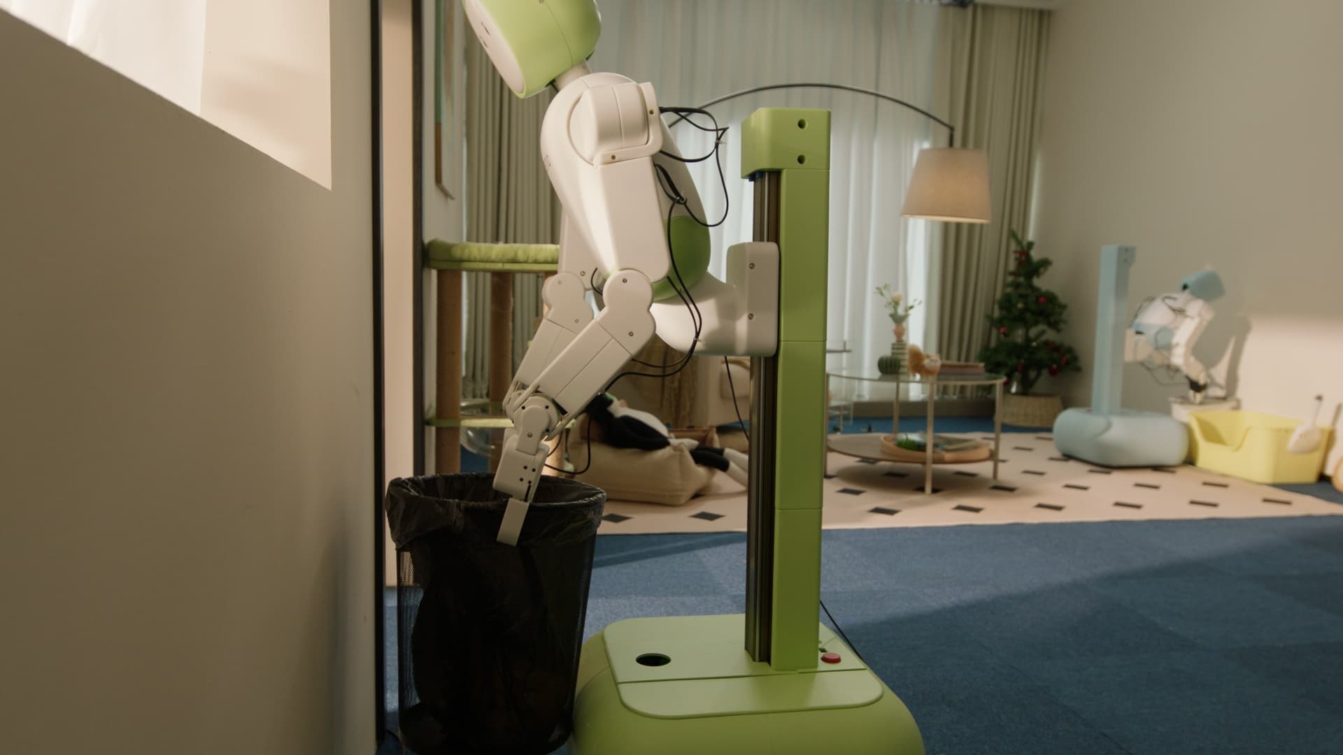 A green Zeno robot placing an item into a bin while another robot works nearby